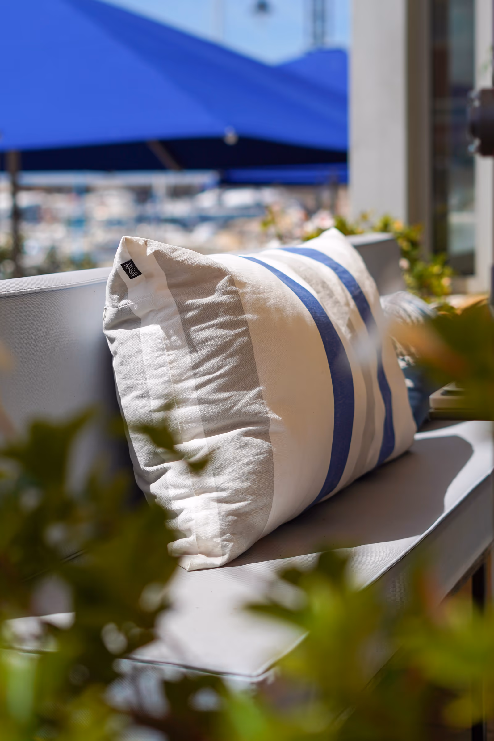 Coussin brodé Nino sur la banquette de la terrasse
